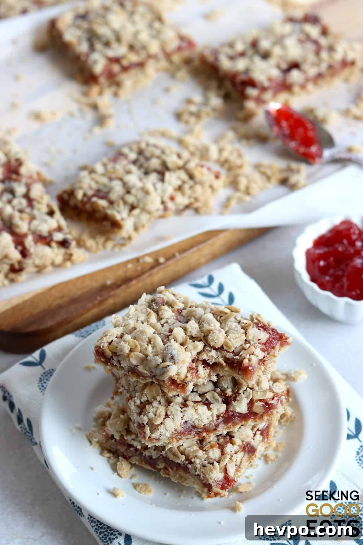 Strawberry oatmeal bars cut into squares, and three stacked on a small white plate.