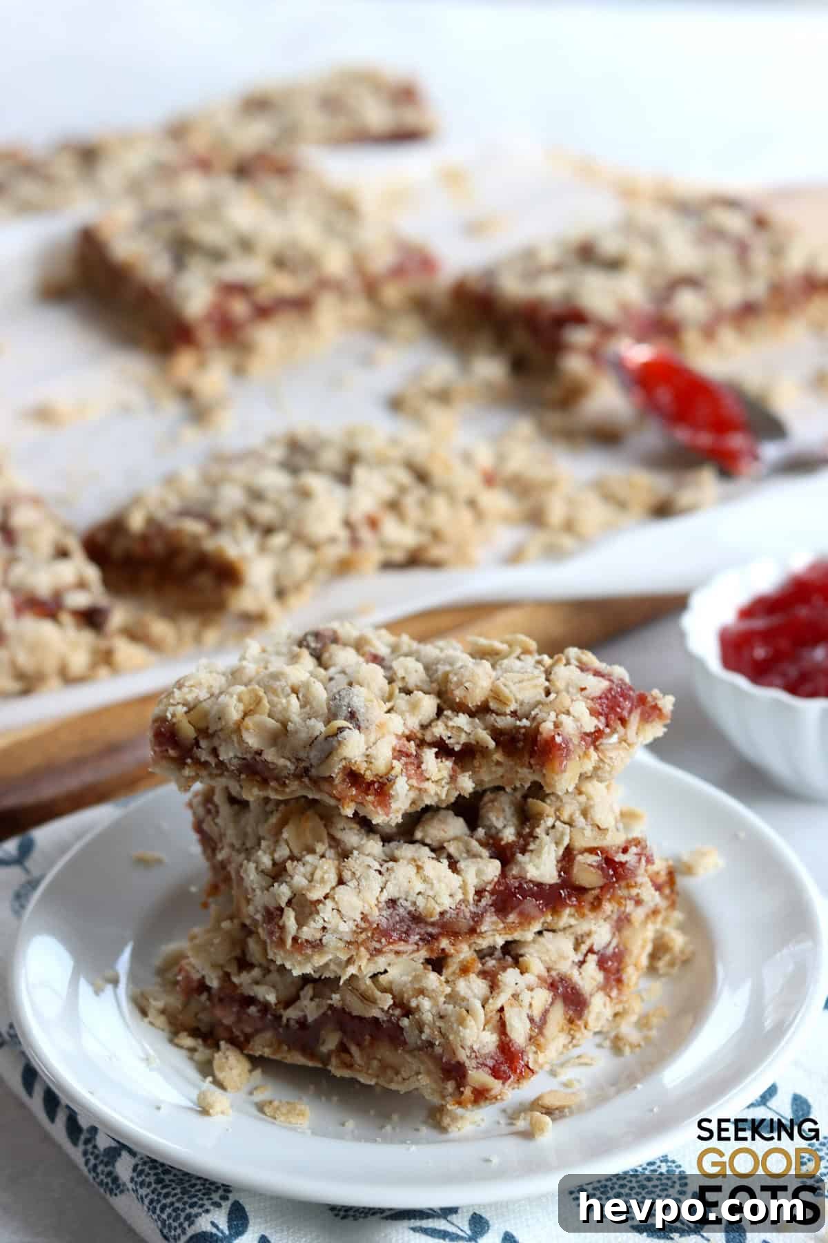 Strawberry oatmeal bars cut into squares, and three stacked on a small white plate.