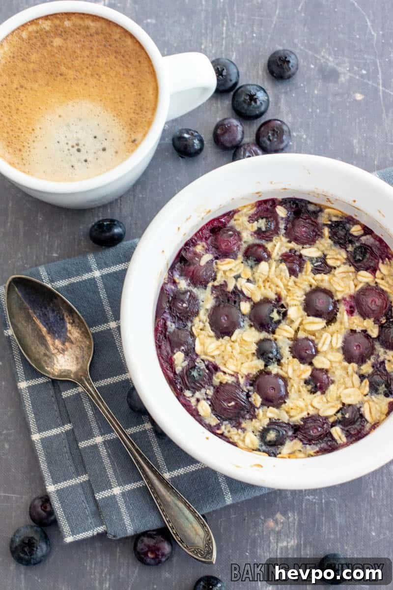 Single-Serve Baked Oats Recipe for One: Quick Breakfast Bowl 2 baked oats for one in a bowl with blueberries with a cup of espresso behind