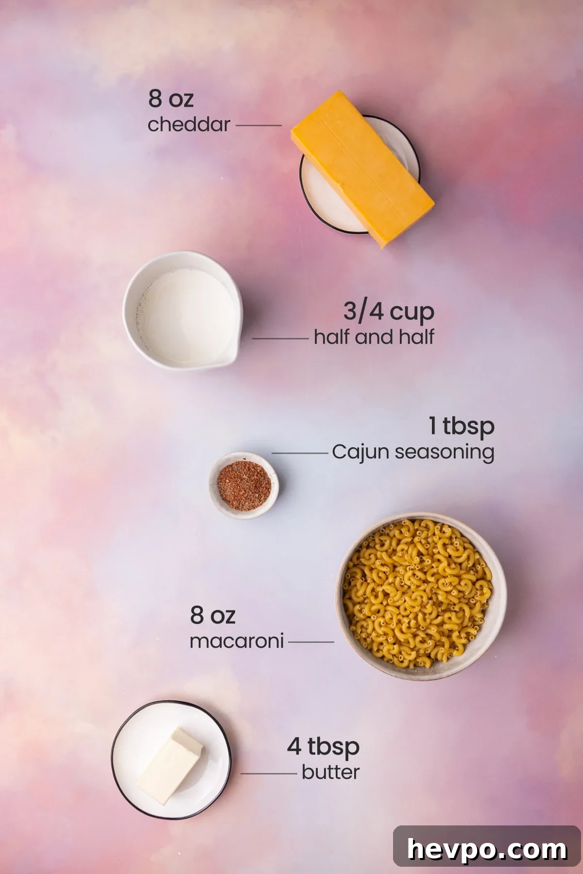 Overhead view of all the ingredients for Cajun Mac and Cheese - cheddar, half and half, Cajun seasoning, macaroni, and butter.