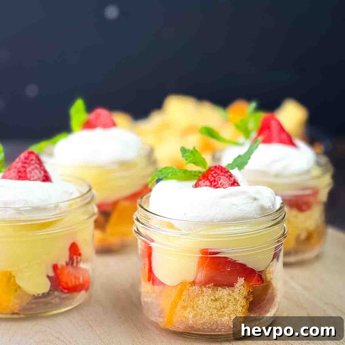 Four parfait jars filled with strawberry shortcake on a serving table.
