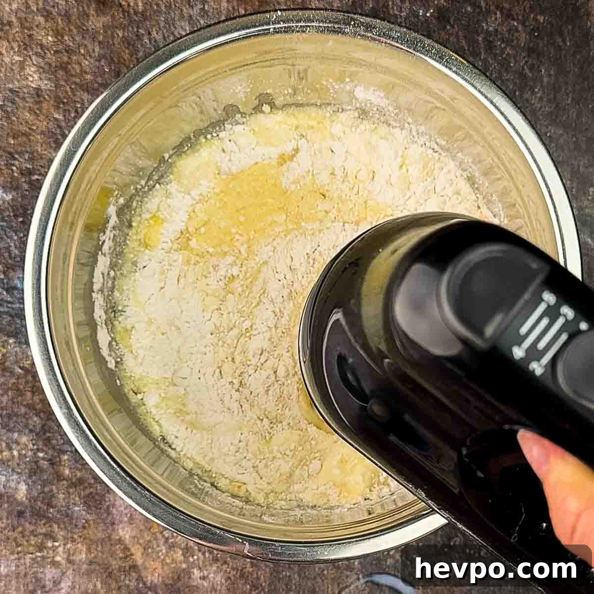 An electric mixer combining the ingredients for the cake mix in a mixing bowl.
