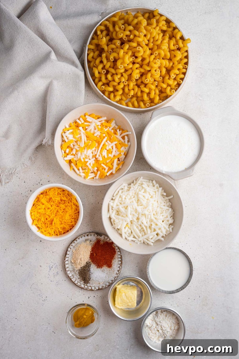Tini’s Viral TikTok Mac and Cheese Recipe 4 An overhead shot of several bowls in various sizes containing ingredients to make Tini's mac and cheese including corkscrew macaroni, shredded cheese blend, heavy cream, evaporated milk, butter, flour, and seasonings.