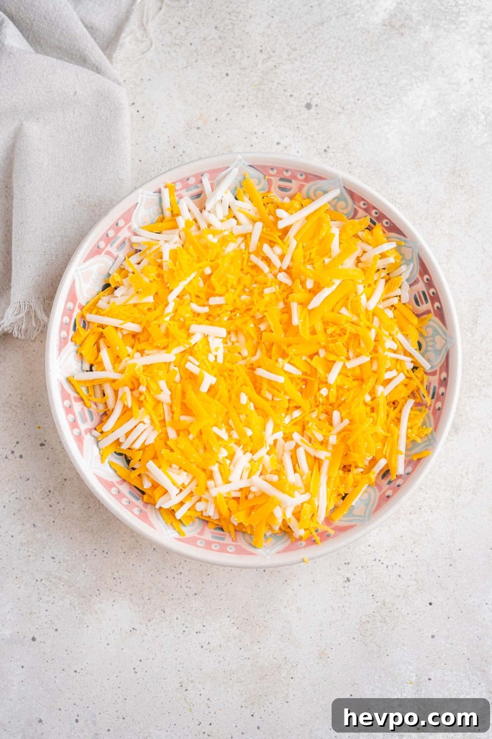 Tini’s Viral TikTok Mac and Cheese Recipe 5 A serving bowl with a shredded cheese blend. The bowl is on a white counter with a white cloth napkin.