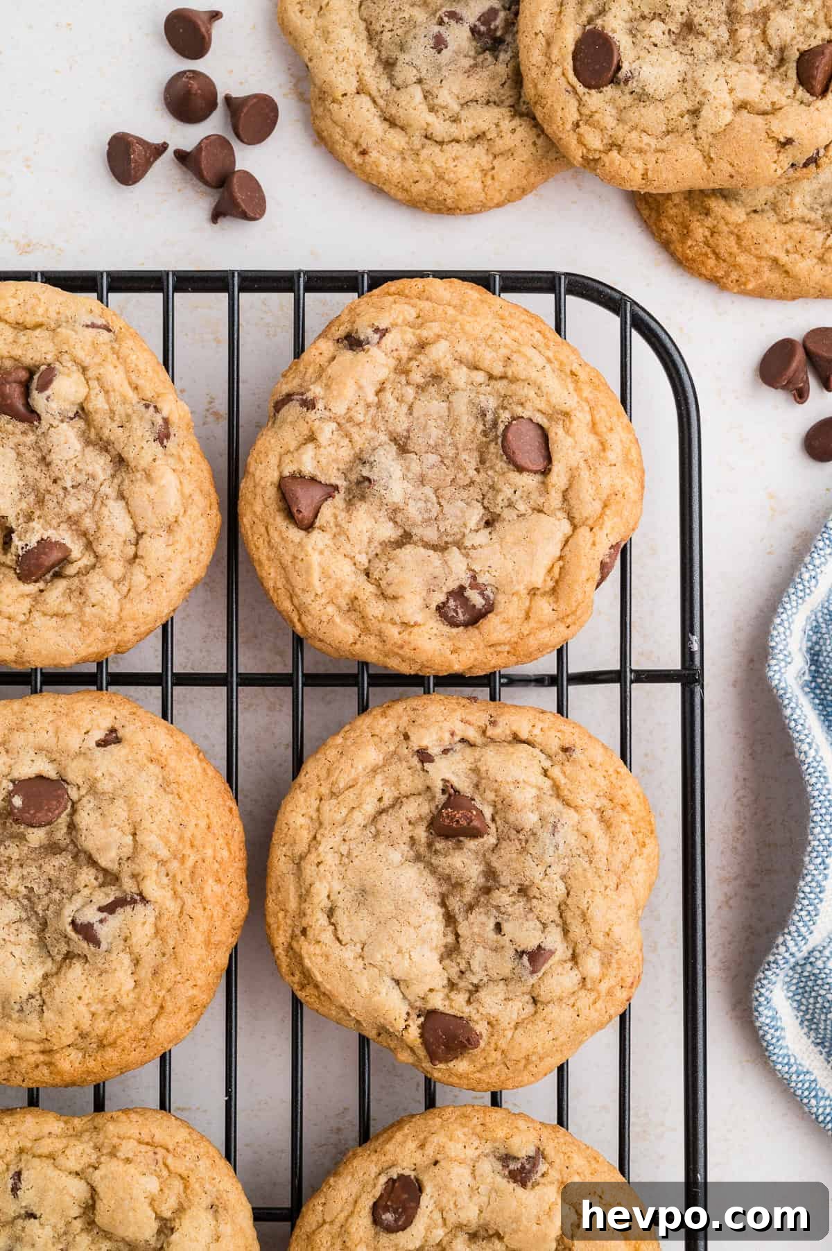 Gluten-Free Chocolate Chip Cookies Loved by Non-GF Eaters 2 Gluten free chocolate chip cookies on a wire rack with chocolate chips off to the side.