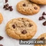 Gluten-Free Chocolate Chip Cookies Loved by Non-GF Eaters 13 Gluten free chocolate chip cookies on a plate with chocolate chips off the plate by the side and milk in the background.
