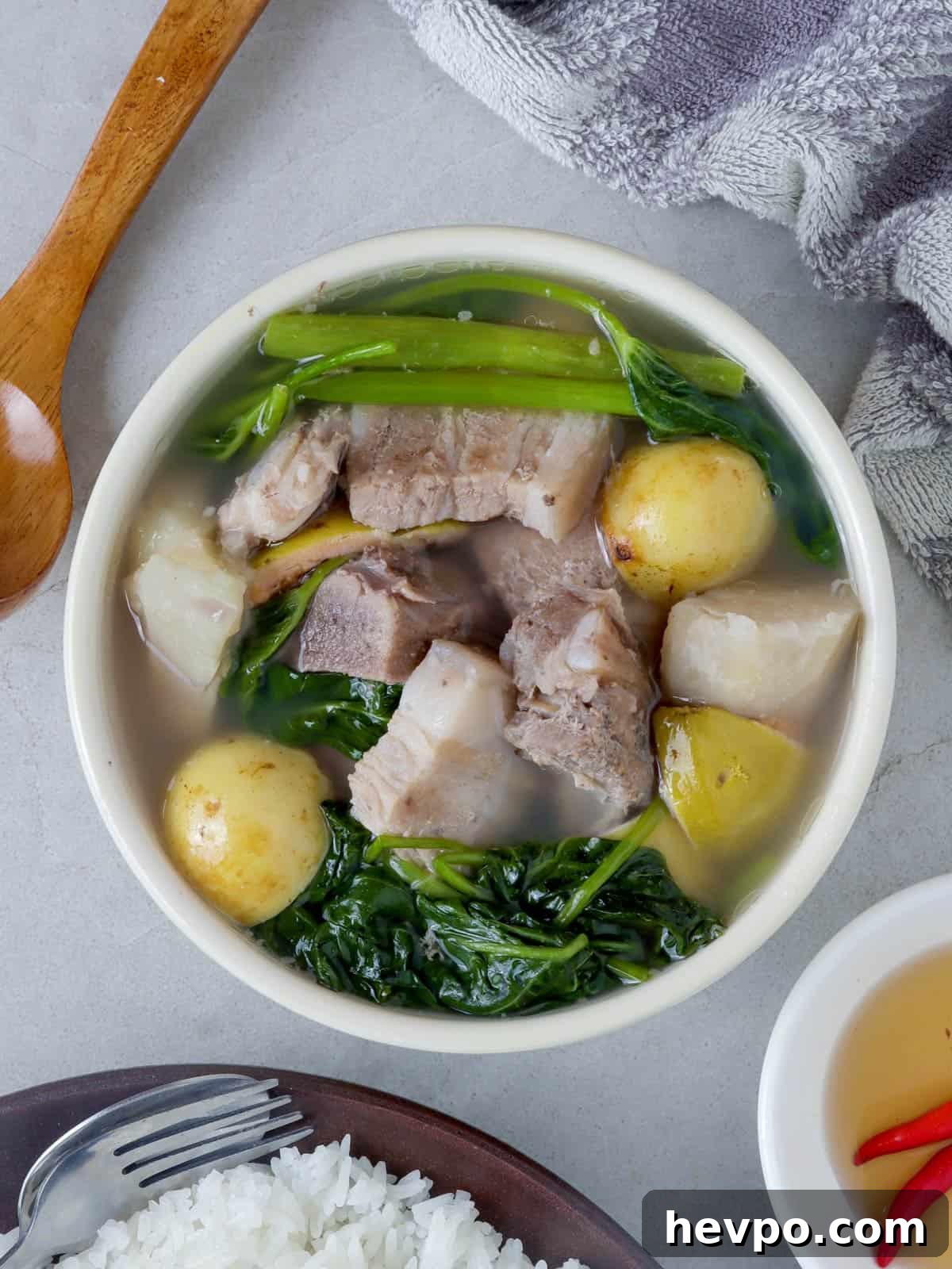 Bulanglang Pork Stew: Filipino Spiced Pork in Sour Broth 6 sinigang na baboy sa bayabas in a white bowl and a plate of steamed rice on the side