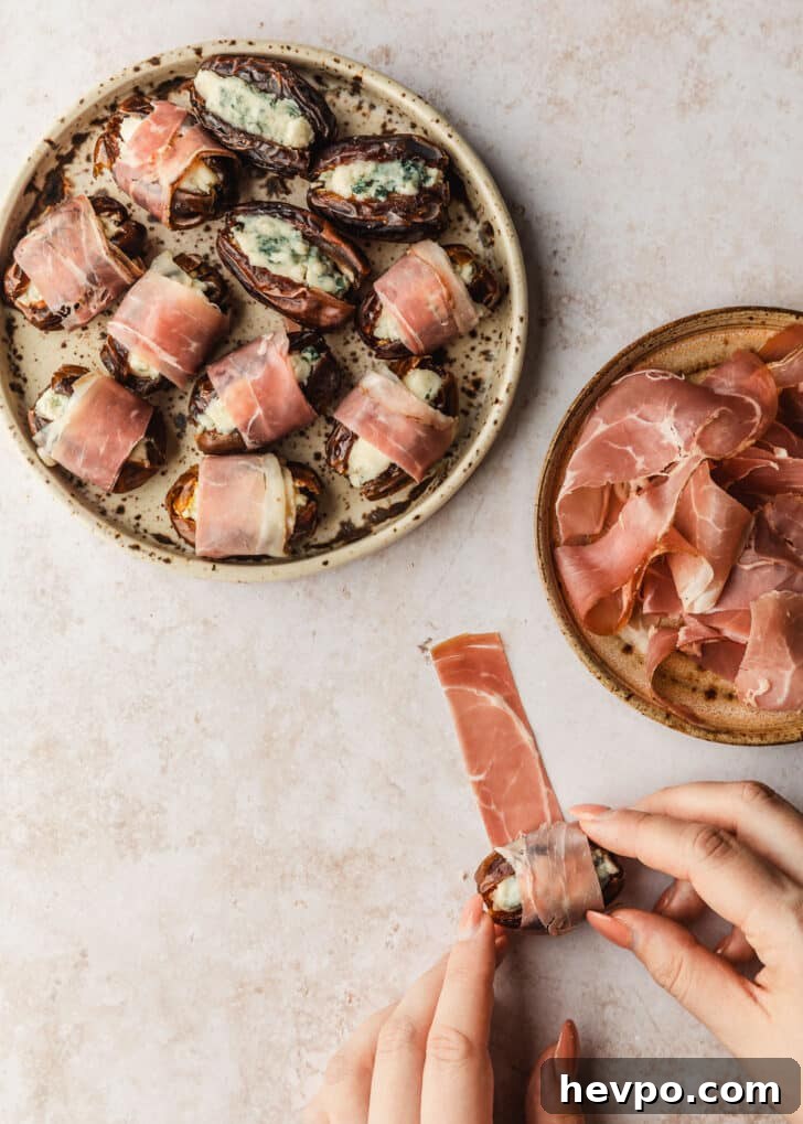Prosciutto-Wrapped Dates with 3 Simple Ingredients 9 Hands rolling dates in prosciutto on a tan counter.