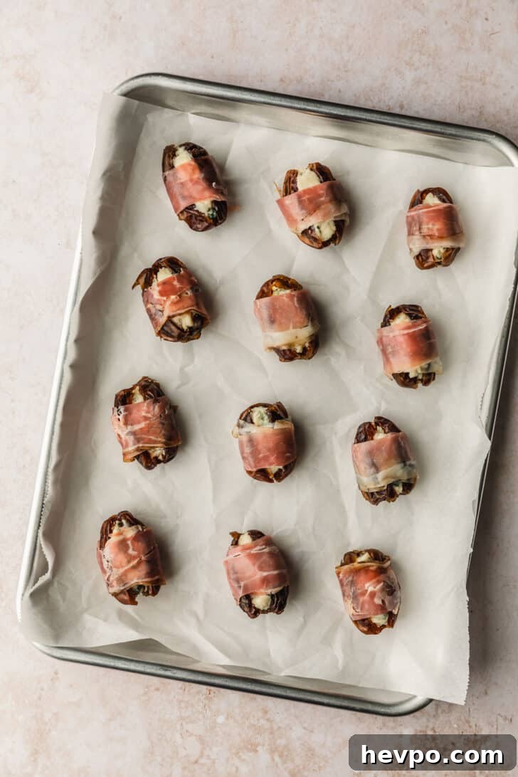 Prosciutto-Wrapped Dates with 3 Simple Ingredients 10 A sheet pan of prosciutto wrapped dates on a tan counter.