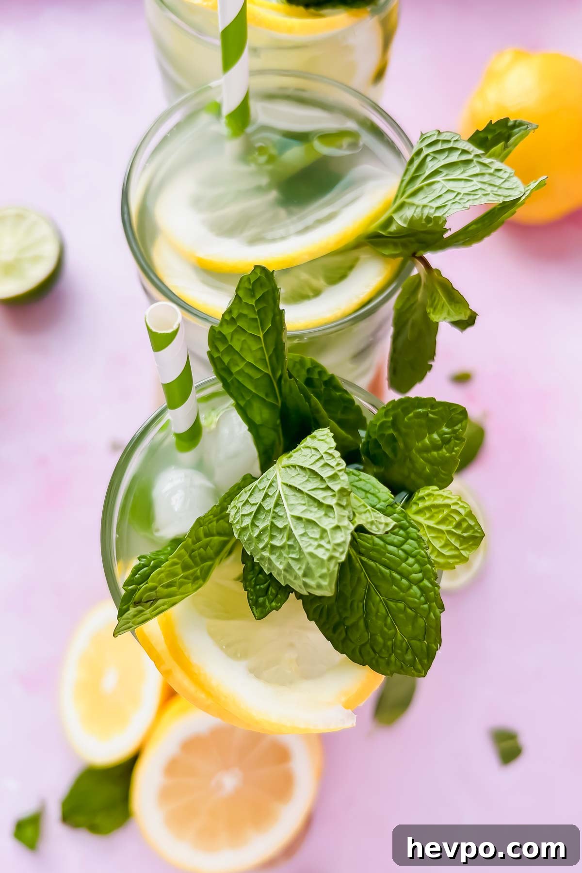 Lemonade Mojito Recipe: Refreshing Low-Calorie Twist 2 two lemonade mojitos garnished with fresh mint and lemon slices in tall glasses on pink background.