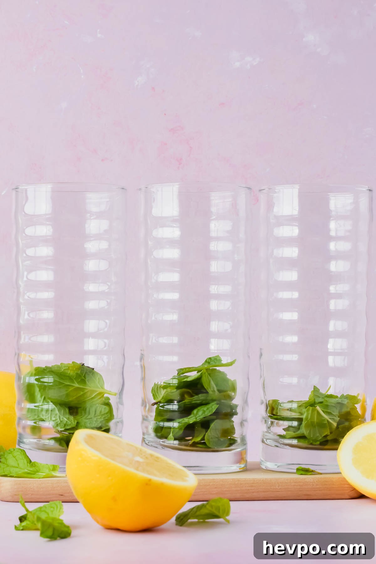 Lemonade Mojito Recipe: Refreshing Low-Calorie Twist 5 three tall glasses filled with fresh mint leaves on pink background.