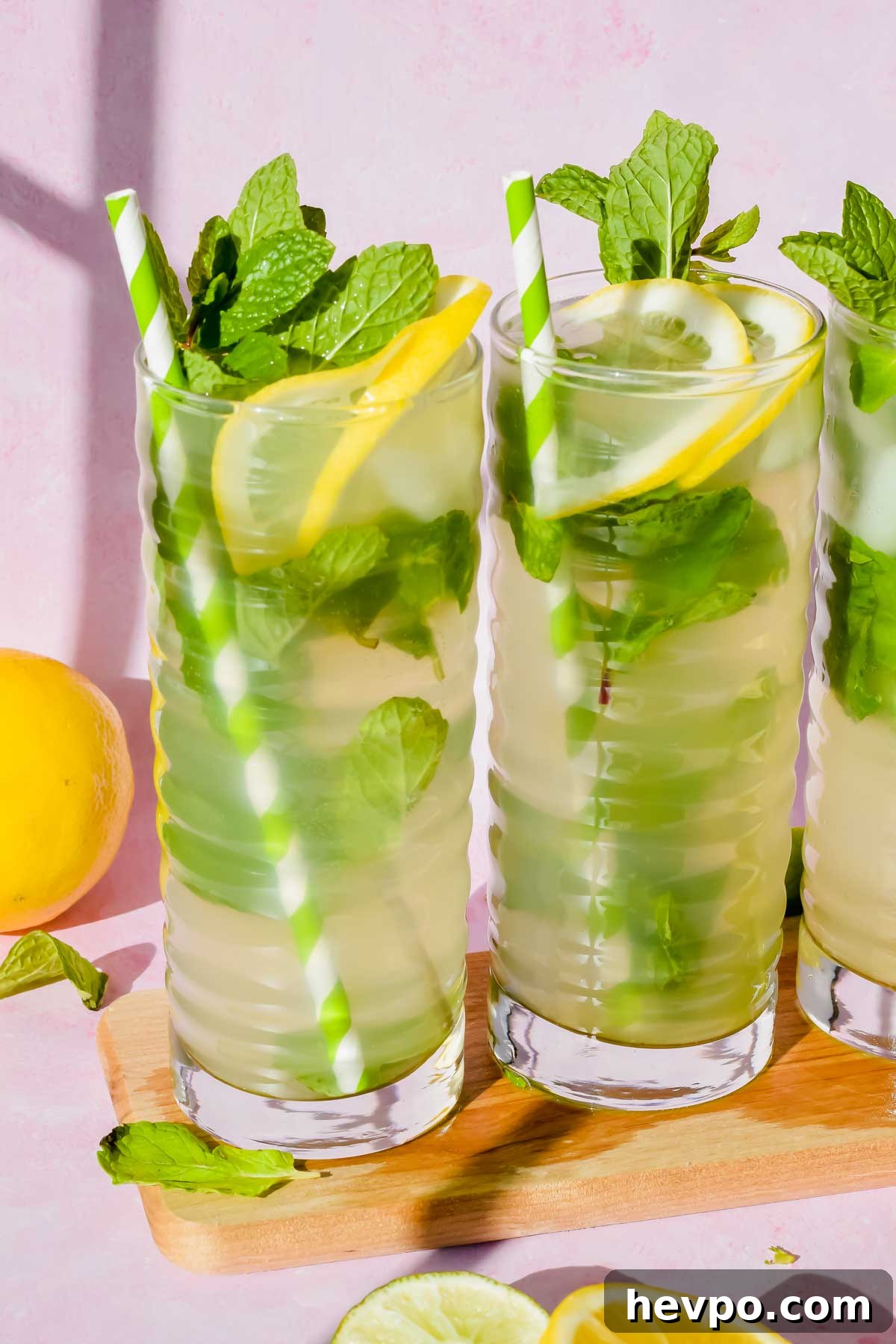 Lemonade Mojito Recipe: Refreshing Low-Calorie Twist 9 skinny lemonade mojitos in tall ribbed glasses garnished with fresh lemons, mint, and a green and white striped straw.