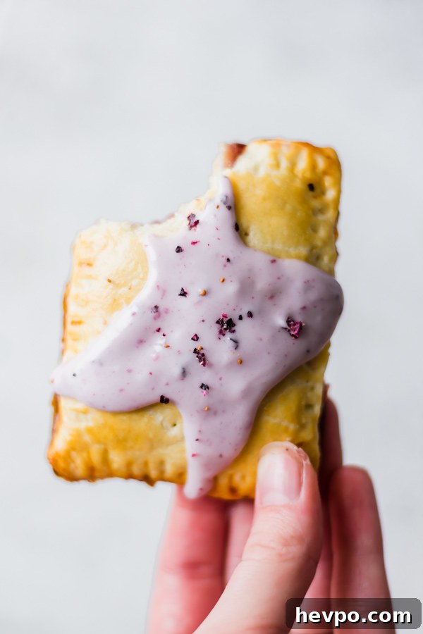 Homemade Blueberry Pop Tarts Hand holding a blueberry poptart with a bite taken out of the top.