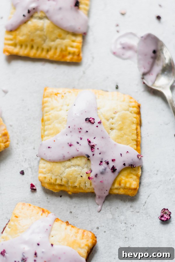 Homemade Blueberry Pop-Tarts Recipe: Flaky, Jam-Filled Pastries 2 Homemade pop tarts topped with light purple blueberry glaze and crushed dried blueberries.