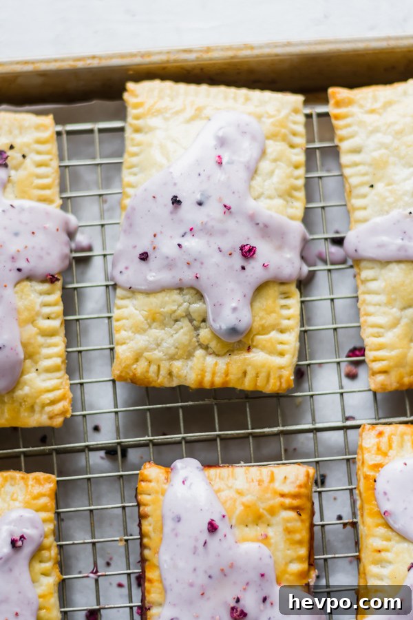 Homemade Blueberry Pop-Tarts Recipe: Flaky, Jam-Filled Pastries 4 Glazed blueberry pop tarts on a cooling rack.