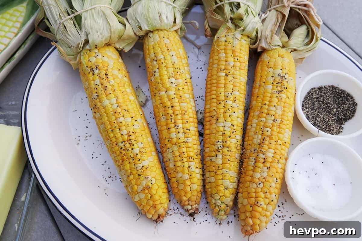 Smoked Corn on the Cob with Garlic Butter Glaze 10 smoked corn seasoned with salt and pepper on white plate