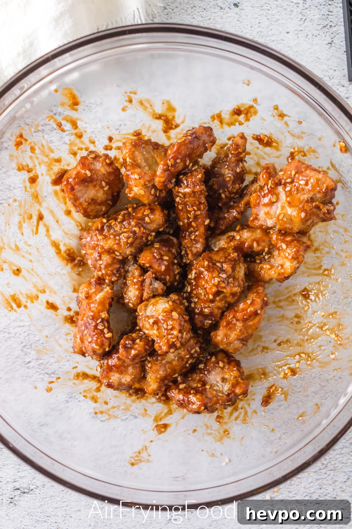 Chicken tossed in sauce and in a bowl before serving.