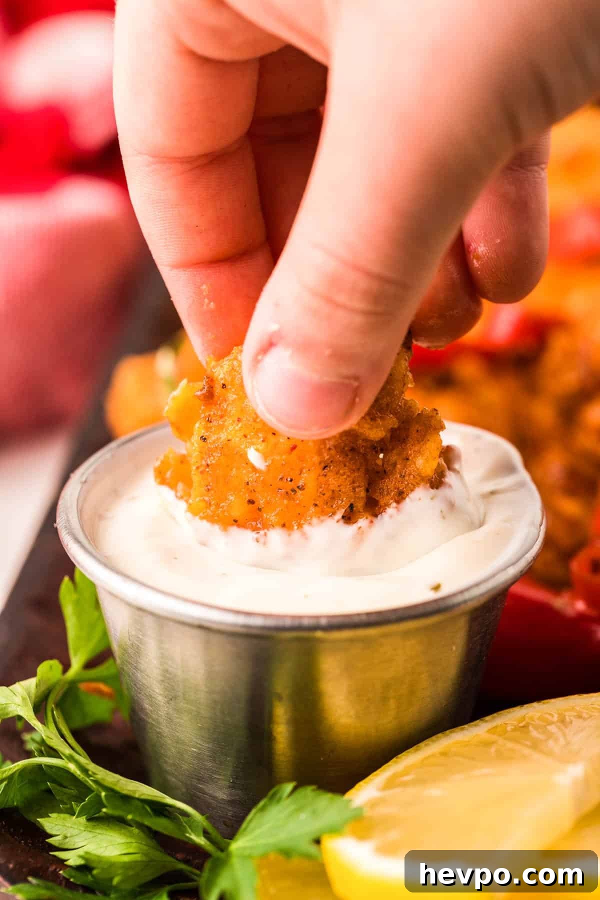LongHorn-Style Wild West Shrimp Recipe: Copycat Steakhouse Dish 3 A woman's hand dipping wild west shrimp into ranch dressing.