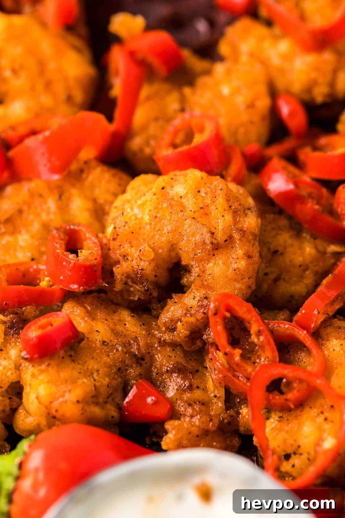 LongHorn-Style Wild West Shrimp Recipe: Copycat Steakhouse Dish 6 Longhorn copycat wild west shrimp on a plate with red chili peppers and dipping sauce.