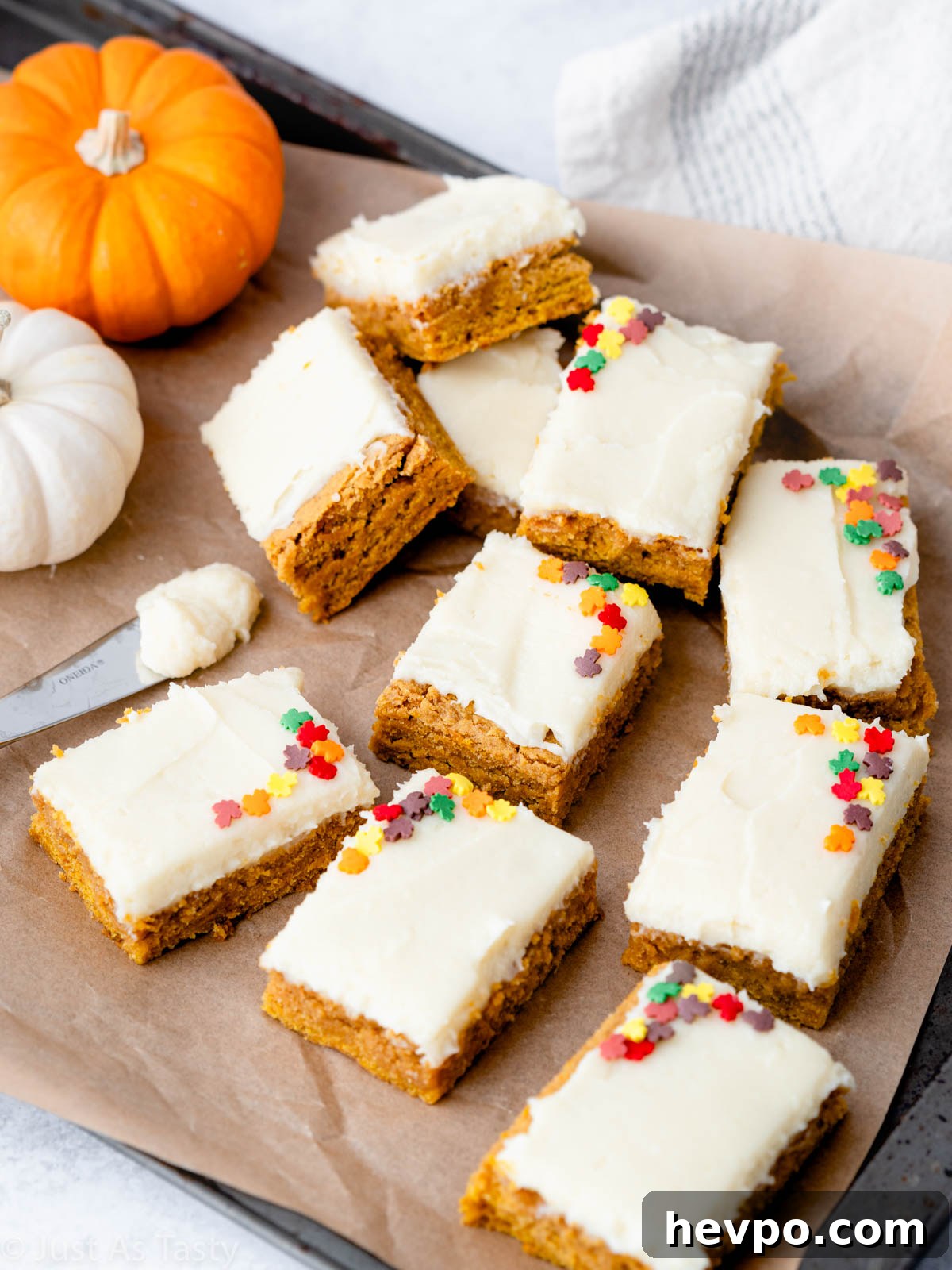 Gluten-Free Pumpkin Bars Recipe for Moist Spiced Squares 2 Frosted pumpkin bars on brown parchment paper.