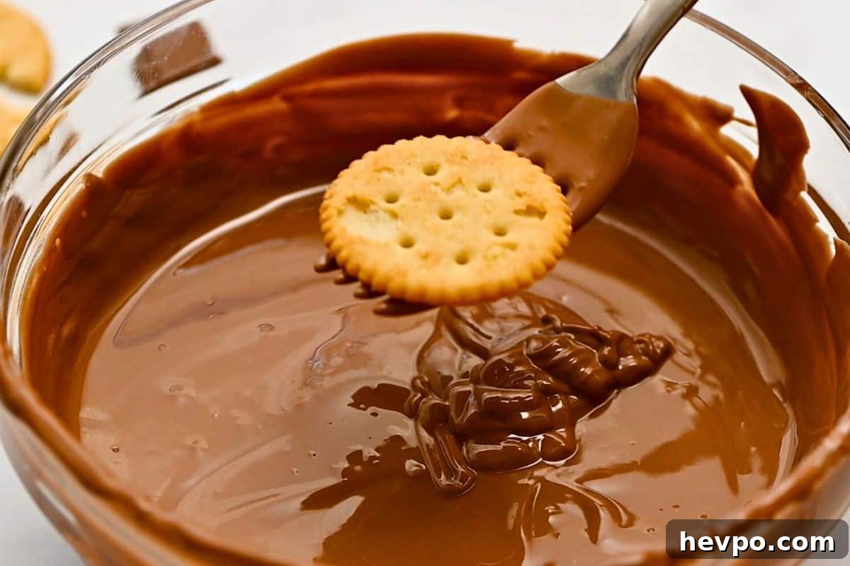 Butter cracker on a fork being dipped into melted chocolate