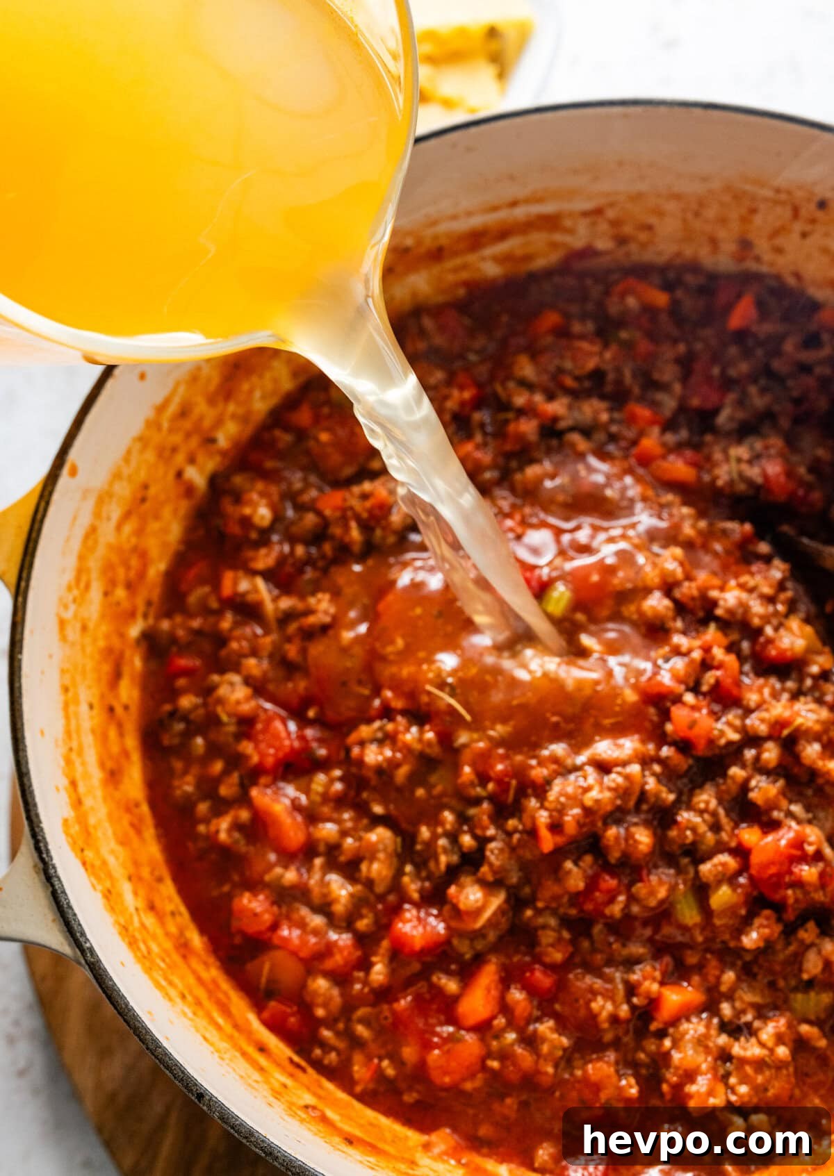 pouring the broth into the pot of lasagna soup.