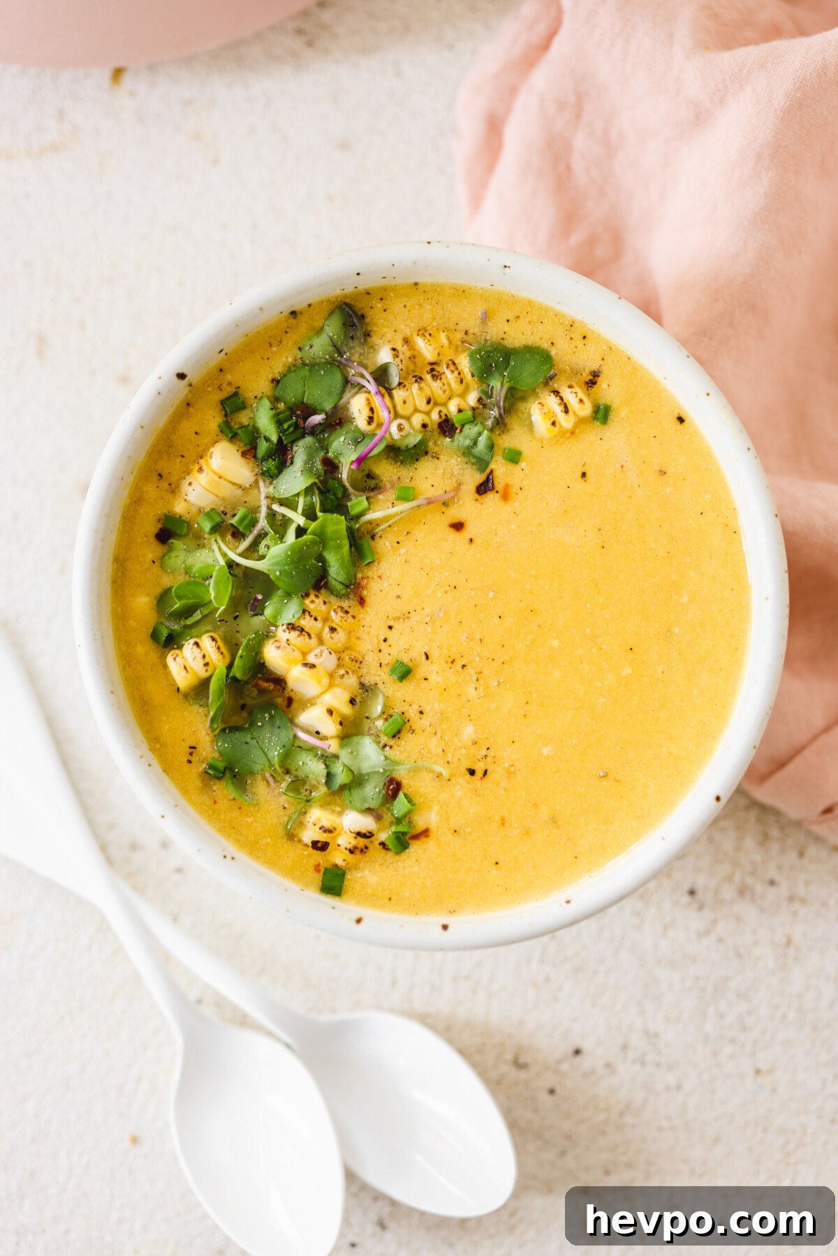 Vegan Corn Chowder in a white bowl topped with charred corn and microgreens