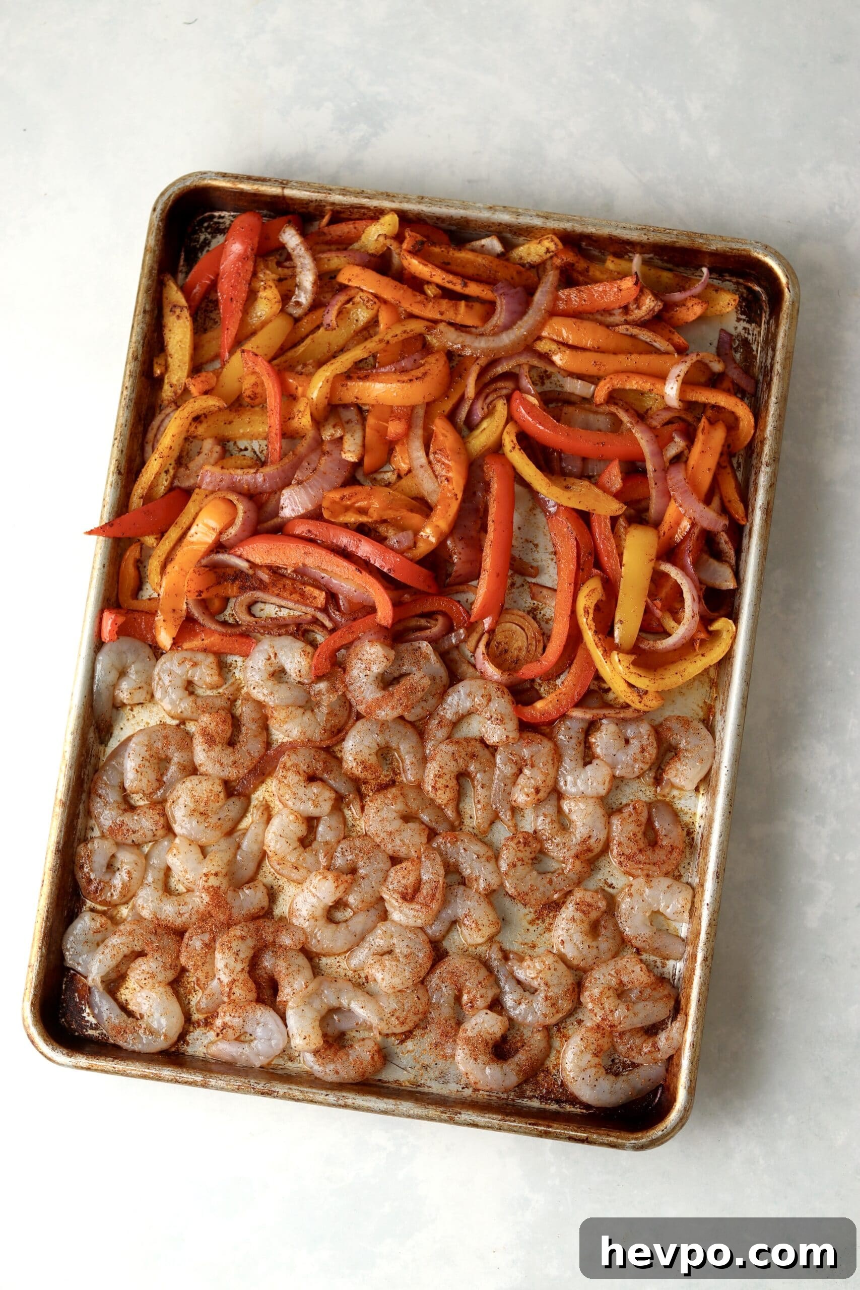 Sheet Pan Shrimp Fajitas with Peppers and Lime Butter 4 raw shrimp with peppers and onions on sheet pan