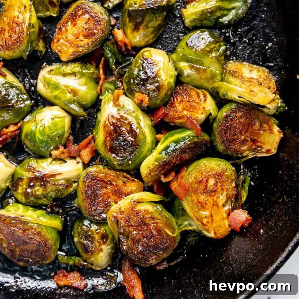 Maple Bacon Recipe with Just 2 Ingredients 15 Pan-fried Brussels sprouts with crispy edges and scattered bacon bits in a skillet.