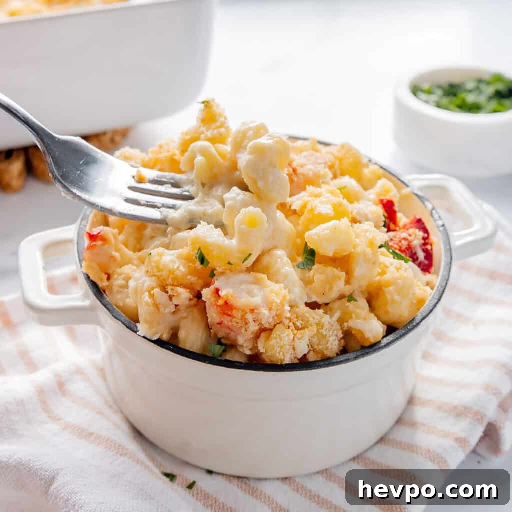 Maple Bacon Recipe with Just 2 Ingredients 17 A fork lifting a portion of creamy lobster mac and cheese from a white dish on a striped cloth.