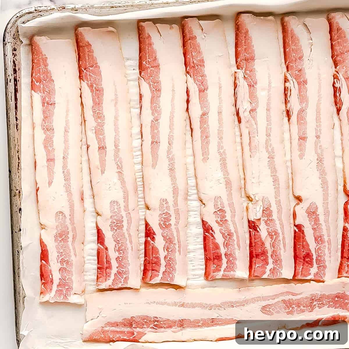 Maple Bacon Recipe with Just 2 Ingredients 4 Raw bacon strips lined on a baking sheet.