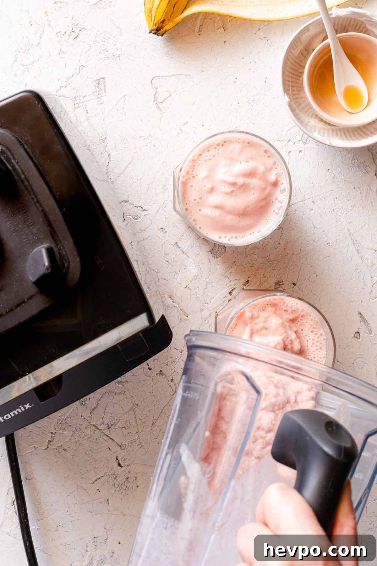 smoothie being poured from blender into 2 glasses