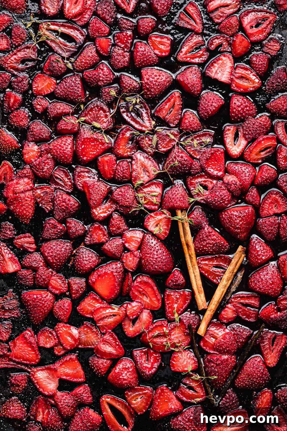 Roasted Strawberries: How to Cook and Use Them for Bold Flavor 8 roasted strawberries with cinnamon sticks, vanilla beans and thyme on a baking sheet.