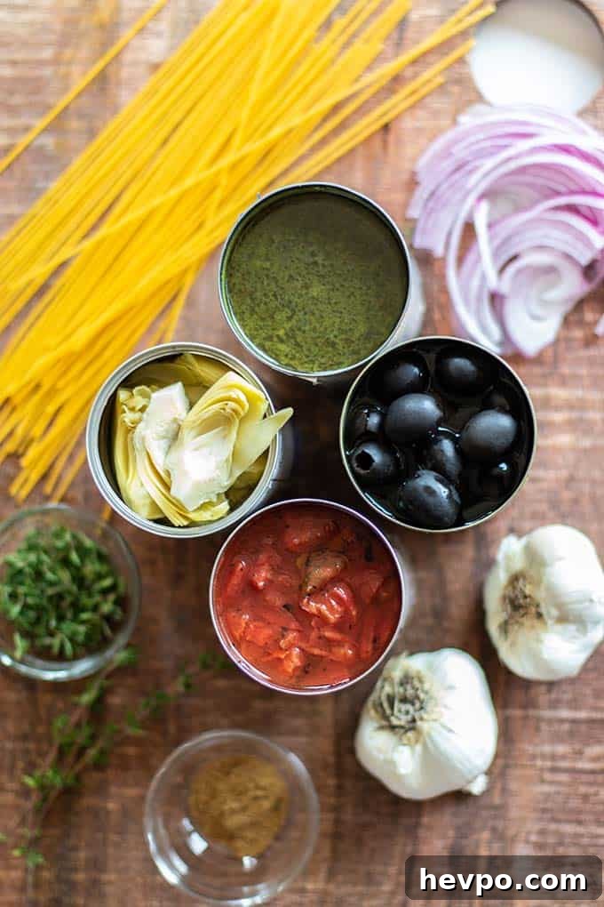 A cutting board with the ingredients for Mediterranean One Pot Pasta, including olives, artichokes, and tomatoes.