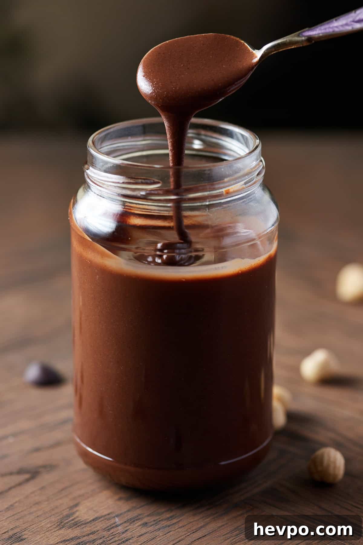 Photo showing a teaspoon drizzling chocolate hazelnut butter from a jar.