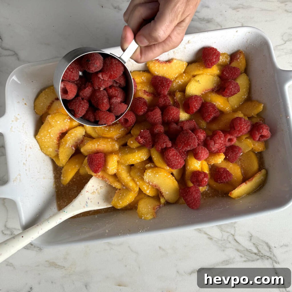 Raspberry and Peach Cobbler with Buttermilk Drop Biscuits 4 Mixing the peaches and raspberries in a baking dish.