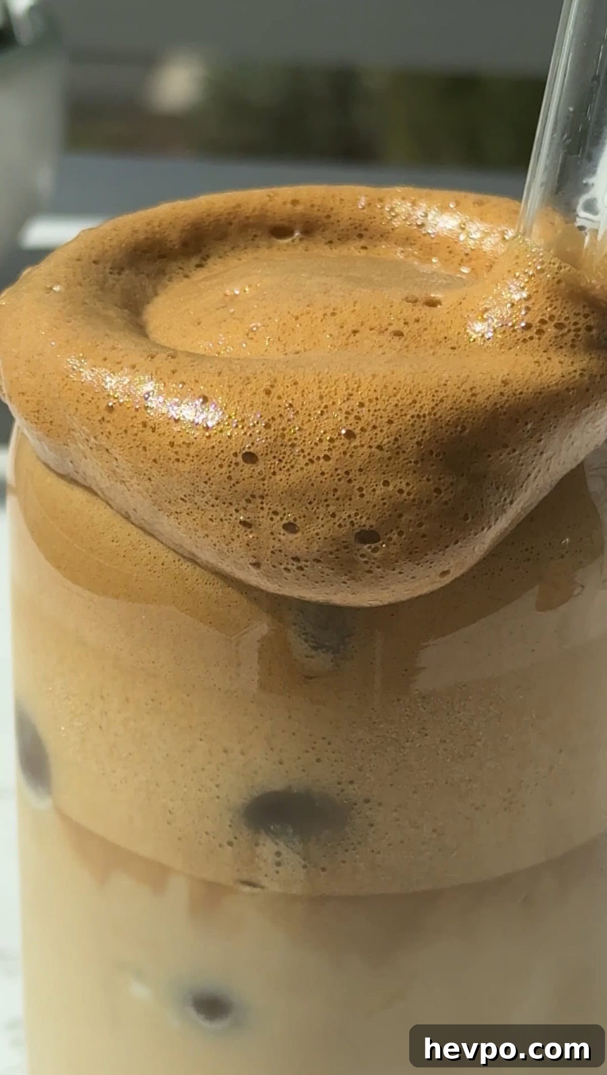 Creamy honey cold foam on top of a glass of iced whipped honey coffee.