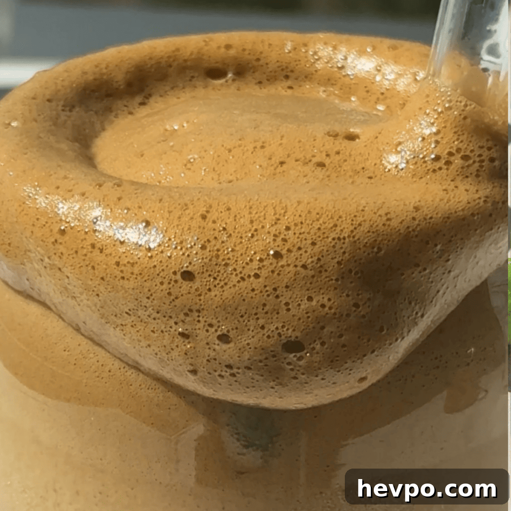 Whipped honey coffee froth dripping over the glass.