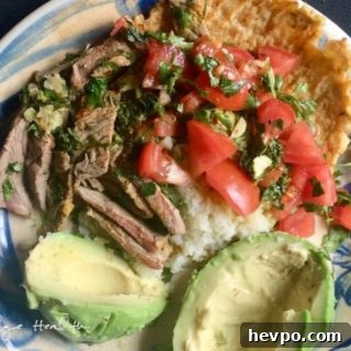 A plate with carne asada and rice, served alongside fresh avocado.